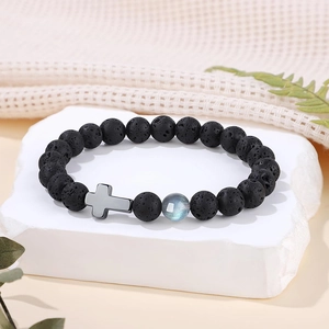 Gros plan d'un bracelet en pierre de lave 8mm avec perle de lune et breloque croix.