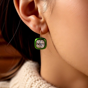 Detail of 18k gold plated earring with green enamel frame and cushion cut clear stone