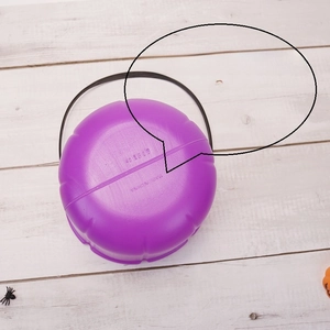 Detailed bottom view of purple Halloween pumpkin candy bucket with black handle and markings