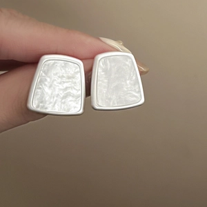 Detail view of geometric trapezoid stud earrings with marble pattern and silver border