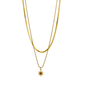 Detail of layered gold snake chain and beaded necklace with sunburst sunburst gemstone pendant