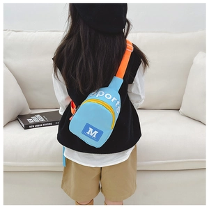 Détail du sac bandoulière enfant bleu clair avec sangle orange porté par un modèle