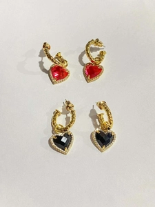 Dettaglio di orecchini a cuore in ottone placcato oro con pietre nere, rosse e micro pavé
