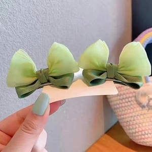 Close-up of mint green double layer organza bow hair clips for baby girls on card
