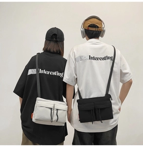 Detailed view of dual-pocket nylon messenger bags in black and white street style