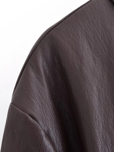 Close-up of deep brown faux leather texture with soft sheen on long belted coat