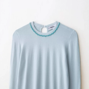 Light blue long sleeve knit top with blue floral sequin beads on the round neck