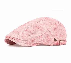 Macro detail of pink vintage newsboy cap showing washed denim texture and bronze metal buckle