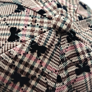 Dettaglio macro del berretto in tweed a quadri rosa con piccoli fiocchi neri in velluto