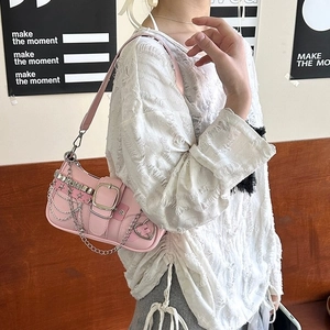 Pink Y2K shoulder bag with star charms and heart buckle worn by model on shoulder