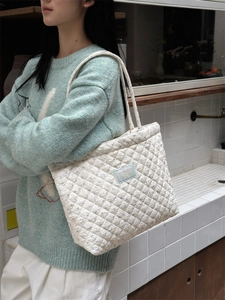 Detailed view of quilted cotton tote bag with purple floral print on a female shoulder