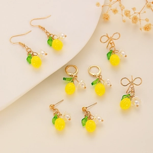 Detailed close-up of yellow lemon earrings with green leaves and white flowers