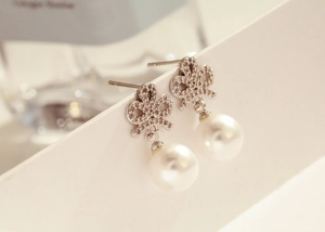 Detailed view of silver bow earrings with micro-pave zircons and elegant white pearls