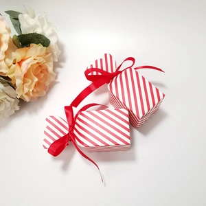 Detail of candy-shaped red striped gift boxes with silk ribbons and decorative roses