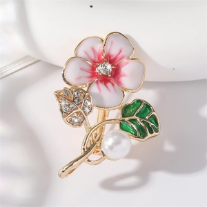 Floral brooch with pink enamel flower, crystal leaf and pearl pendant on white surface