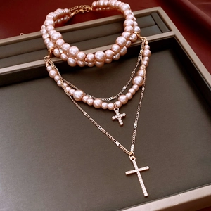 Macro view of multi-layer rose gold cross pendants with pink pearls and shiny diamonds