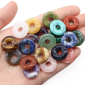 Hand holding assorted 18mm natural crystal agate donut pendants in vibrant colors