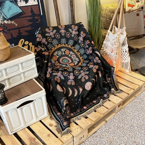 Close-up of bohemian mandala moon phase throw blanket with decorative beige tassels