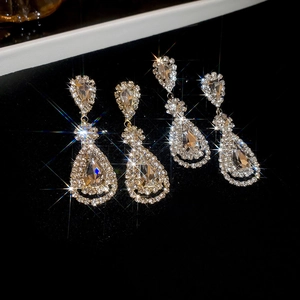 Detailed close-up of water drop fringe earrings with sparkling crystals on black velvet