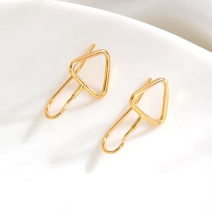 Detailed view of minimalist gold geometric arrow-shaped earrings on white ceramic tray