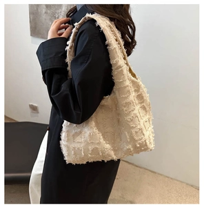 Detailed macro view of beige quilted canvas tote bag with textured fringe grid pattern