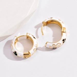 Close-up of vintage white enamel flower hoop earrings on a white marble background