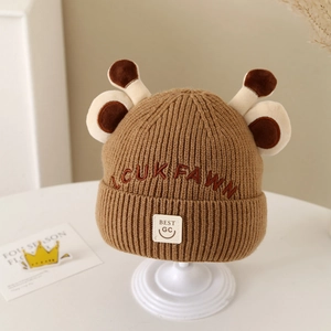 Close-up of thick knit winter baby hat with plush antlers and embroidered brand label