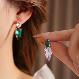 Elegant emerald and lavender pear-cut drop earrings with gold prong setting on model