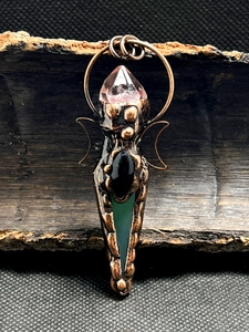 Detail of handcrafted copper wire pendant with amethyst and colorful agate stones