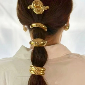 Macro shot of minimalist gold metal hair cuff and curved knot hair clips on a ponytail