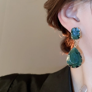Close-up of vintage dark green teardrop and square earrings with elegant gold plating