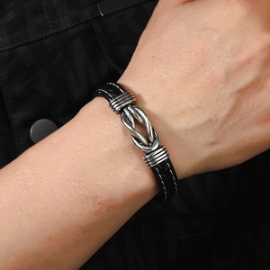 Close-up of a woven black leather bracelet with silver metal knot worn on a man's wrist