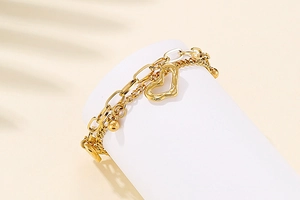 Détail d'un bracelet multicouche en acier doré avec breloques cœur et petites perles