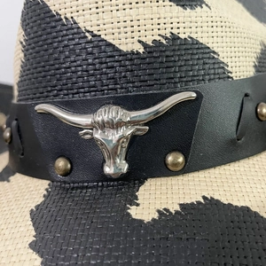 Detail of cowhide band with silver bull head buckle and studs on a woven cowboy hat