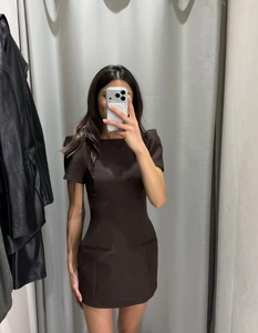 Detail of slim fit dark brown mini dress with puff sleeves shown in fitting room