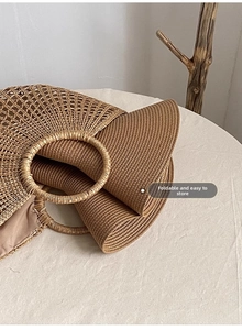 Gros plan d'un sac à main pliable en paille tressée marron avec une poignée ronde