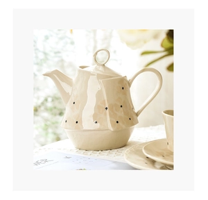 Gros plan d'une théière irrégulière en céramique beige avec motif floral et bouton