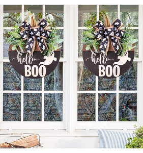Halloween wooden sign with ghost design and eucalyptus leaves hanging on a white window