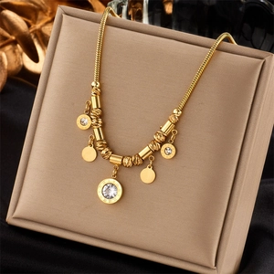 Close-up of gold snake chain necklace with Roman numeral ring and crystal pendant