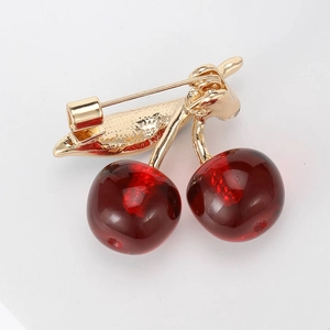 Cute cherry brooch featuring red fruit and gold leaves on a clean white background