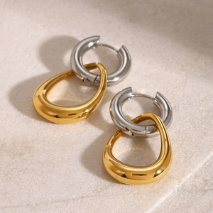 Detailed view of silver hoop earrings with gold teardrop pendants in metallic finish