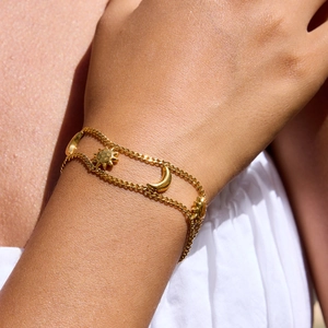 Detail of 18K gold stainless steel double chain bracelet with sun and moon charms on wrist