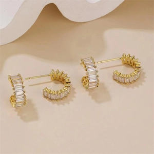 Gros plan de boucles d'oreilles dorées en C avec cristaux rectangulaires clairs