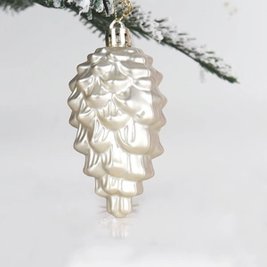 Golden pinecone Christmas tree ornament with metallic finish on a festive snowy branch