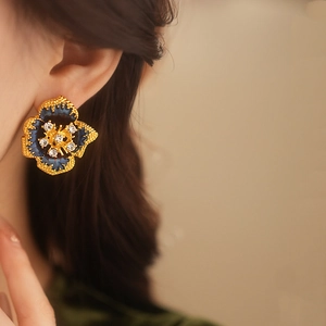 Close-up of vintage gold flower earrings with blue enamel and sparkling rhinestones