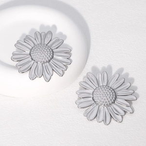 Macro detail of silver stainless steel sunflower studs on a white ceramic plate