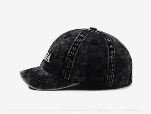 Detail view of washed black baseball cap featuring vintage embroidery and cotton texture