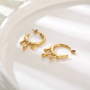 Minimalist gold-plated liquid lava earrings in fluid metal design on a white tray