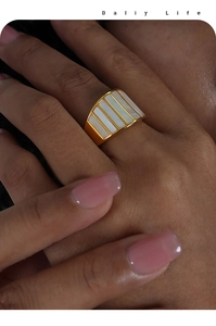 Detailed view of wide gold index finger ring with six white rectangular shell-like inlays