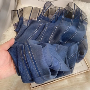 Detail of dark blue silk wool scarf with elegant gold metallic stripes and sheer texture